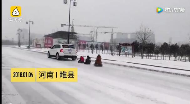 河南大雪过后男子驾车雪上跑 车后用轮胎拖3孩子滑雪